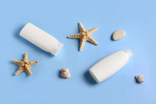 Bottles of sunscreen cream with seashells and starfishes on blue background