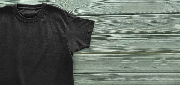 テキストのためのスペースと木製の背景に空白の黒いTシャツ — ストック写真