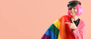 LGBT bayrağı olan güzel genç bir kadın bej arka planda mesaj için yeri olan bir şeyi işaret ediyor.
