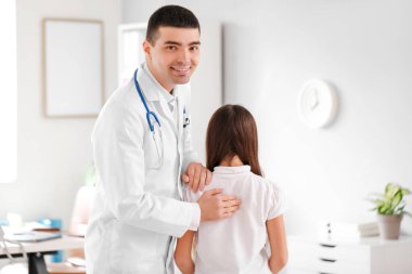 Doktor klinikteki küçük kızın duruşunu kontrol ediyor.