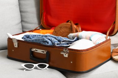 Oturma odasındaki kanepede kadın kıyafetleriyle birlikte valizi aç, yakın plan.