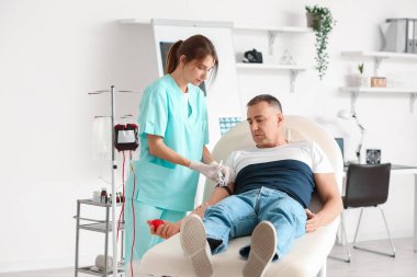Klinikte olgun donörden kan alan kadın hemşire.