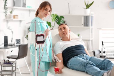 Klinikte olgun donörden kan alan kadın hemşire.