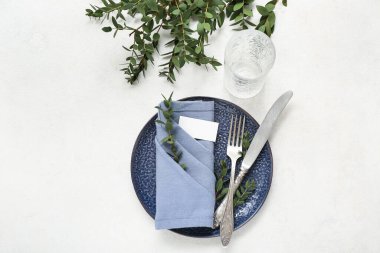 Beyaz arka planda katlanmış peçete, boş kart ve çatal bıçak takımı.