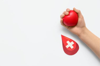 Beyaz arka planda haçlı kağıt ve kan damlaları tutan bir kadın. Dünya Bağış Günü