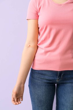 Leylak arka planında uygulamalı tıbbi yaması olan bir kadın, yakın plan. Dünya Kan Bağışı Günü