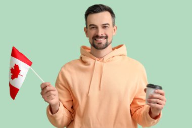 Kanada bayrağı ve yeşil arka planda kahve fincanı olan yakışıklı adam.