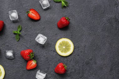 Limonlu taze çilek ve siyah arka planda buz.