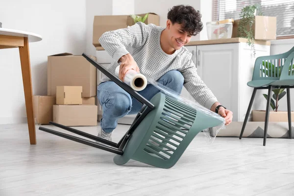 Young Man Wrapping Chair Stretch Film Kitchen — Stock Photo, Image