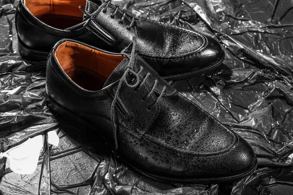 Stylish classic male shoes with water drops on black background