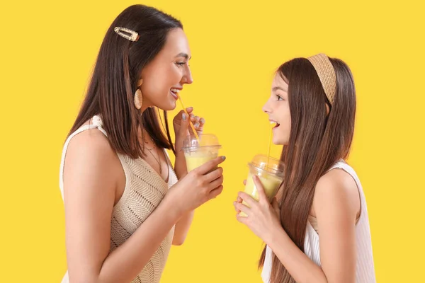小さな女の子とともに彼女のお母さん飲むスムージーオン黄色の背景 — ストック写真