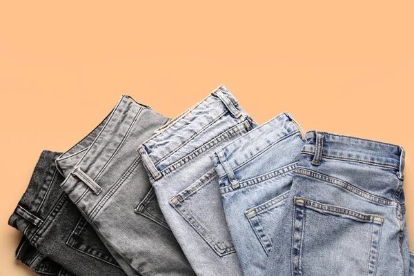 Different Stylish Folded Jeans Pale Orange Background — Stock Photo, Image
