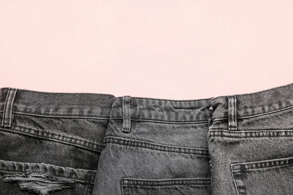 ピンクの背景に異なる折り畳まれたダークジーンズ — ストック写真