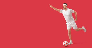 Kırmızı arkaplanda futbol oynayan adam metin için boşluk yaratıyor
