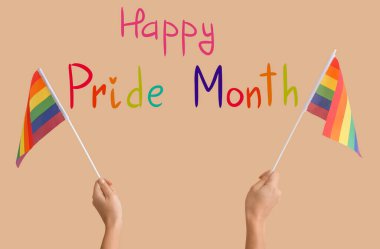 Bej arka planda LGBT bayrakları olan kadın eller. Mutlu Gurur Ayı