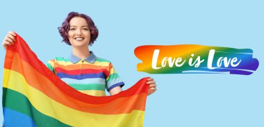 Açık mavi arka planda LGBT bayrağı olan genç bir kadın. Mutlu Gurur Ayı