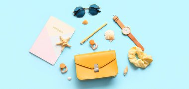 Açık mavi arkaplanda defter ve aksesuarlı şık çanta