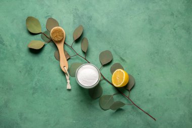 Renkli arkaplanda bir kase kabartma tozu, temizlik fırçası, limon ve okaliptüs dalı