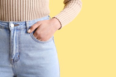 Young woman in stylish jeans on yellow background, closeup clipart