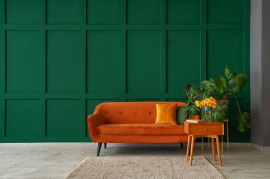 Oturma odasının içinde, sehpanın üzerinde kahverengi kanepe ve narsist çiçekler var.