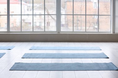 Spor salonunun penceresinin yanındaki yerde yoga minderleri var.