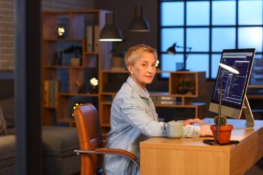 Olgun kadın programcı geceleri ofiste çalışıyor.