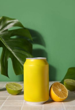 Yeşil duvarın yanındaki masada turunçgil meyveli soda ve palmiye yaprağı var.