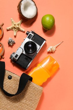 Plaj çantası, aksesuarlar, deniz kabukları ve kırmızı arka planda meyveler.