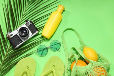 İçinde meyve, plaj aksesuarları ve yeşil arka planda palmiye yaprağı olan ip torbası.