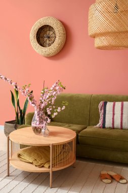 İçinde yeşil kanepe ve kahve masasında çiçek açan sakura dalları olan rahat bir oturma odası.