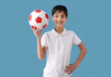 Mavi arka planda futbol topu olan küçük çocuk.