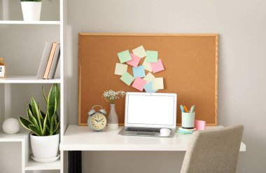 Masada yapışkan notlar ve dizüstü bilgisayarlı bir tahta var.