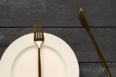 Altın çatallı ve siyah ahşap kaplama bıçaklı bir tabak.