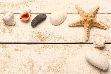 Beyaz ahşap zemin üzerinde kum bulunan deniz yıldızından ve deniz kabuklarından yapılmış çerçeve