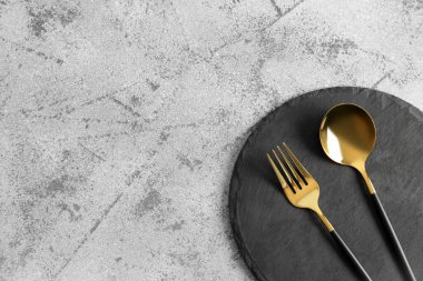 Gri zemin üzerinde çatal ve altın kaşık olan tahta