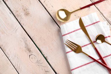 Beyaz ahşap arka planda kırmızı saplı altın çatal bıçak takımı