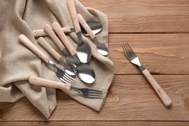 Ahşap arka planda plastik saplı paslanmaz çelik çatallar ve kaşıklar