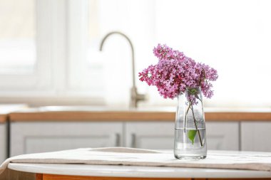 Mutfaktaki masada leylak çiçekli vazo.