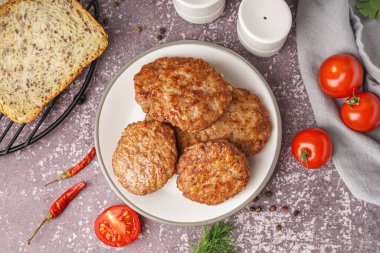 Mutfaktaki grunge masasında pirzola, domates ve biber tabağı.