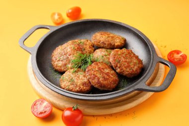 Pirzolalı tava, dereotu ve domatesler sarı arka planda.