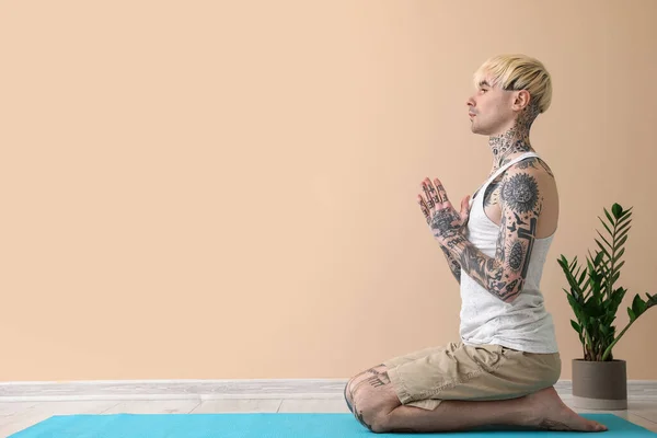 Tatuado Jovem Meditando Perto Parede Bege — Fotografia de Stock