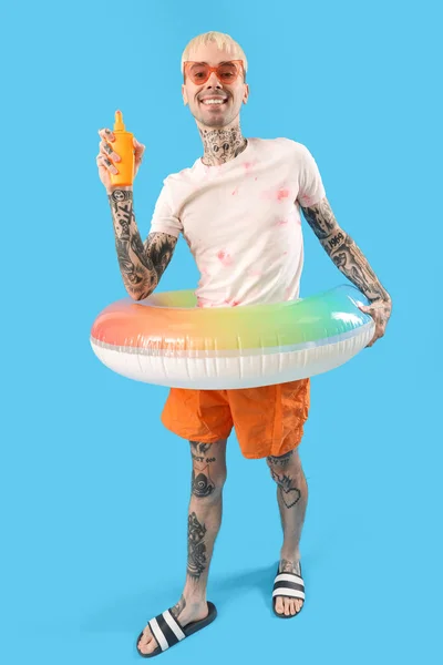 Homem Tatuado Com Protetor Solar Creme Anel Natação Fundo Azul — Fotografia de Stock