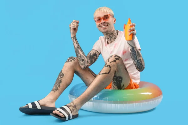 Tattooed Man Sunscreen Cream Swimming Ring Light Blue Background — Stock Photo, Image