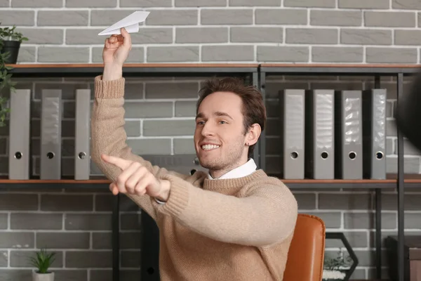 若い男がオフィスで紙飛行機を投げる — ストック写真