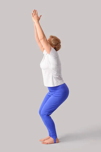 Sportliche Reife Frau Praktiziert Yoga Auf Hellem Hintergrund — Stockfoto