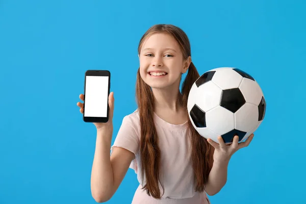 Liten Flicka Med Fotboll Och Mobiltelefon Blå Bakgrund — Stockfoto