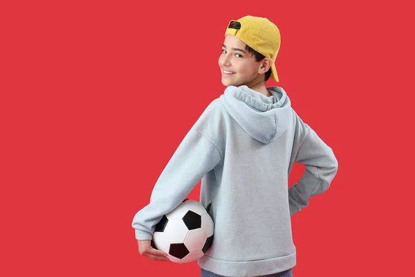 赤い背景にサッカーボールを持つ小さな男の子 — ストック写真