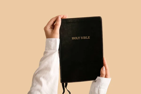 stock image Female hands with Holy Bible on pale orange background