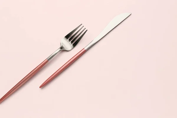 白色背景的带粉色把手的不锈钢叉子和刀片 — 图库照片
