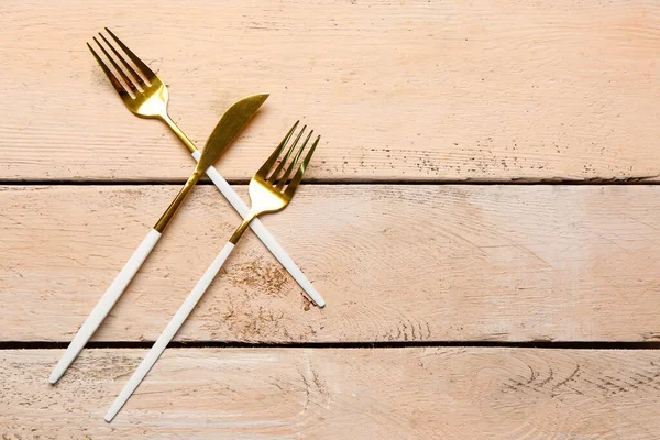 金色のフォークと白い木製の背景に色のハンドルのナイフ — ストック写真
